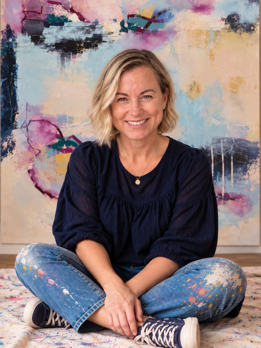 Nicola Bird seated in front of the abstract painting Reciprocity